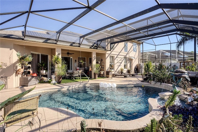 view of pool with pool water feature, glass enclosure, ceiling fan, and a patio