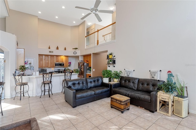 tiled living room with ceiling fan and a towering ceiling