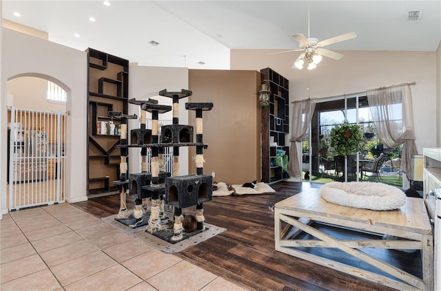 exercise room with ceiling fan, light tile patterned floors, and high vaulted ceiling