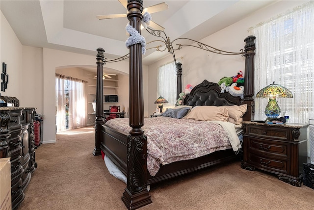 carpeted bedroom with a tray ceiling and ceiling fan