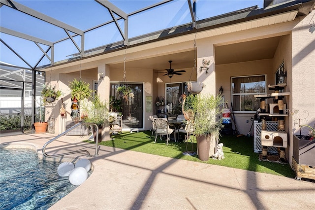 rear view of house featuring glass enclosure, ceiling fan, and a patio