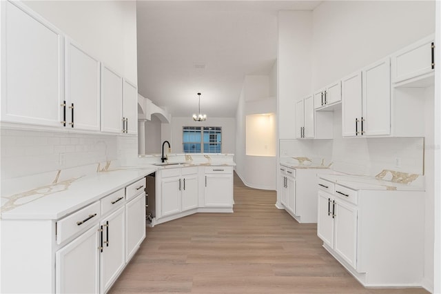 kitchen featuring kitchen peninsula, sink, white cabinets, and decorative light fixtures