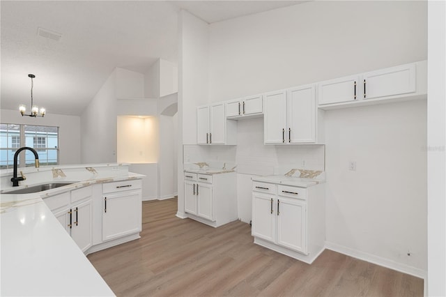 kitchen featuring sink, hanging light fixtures, tasteful backsplash, light hardwood / wood-style floors, and white cabinetry