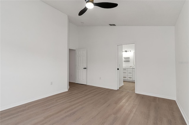 unfurnished bedroom featuring ceiling fan, light wood-type flooring, ensuite bathroom, and lofted ceiling