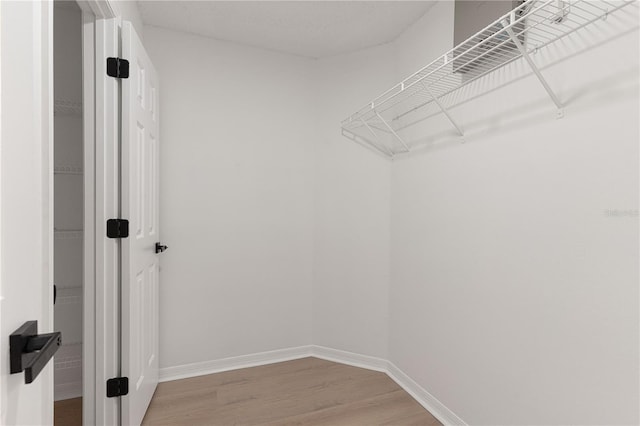 walk in closet with hardwood / wood-style flooring