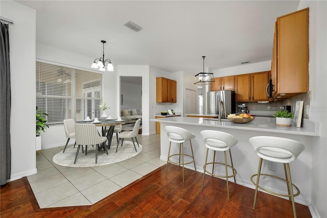 kitchen featuring sink, decorative light fixtures, a kitchen bar, light tile patterned floors, and appliances with stainless steel finishes