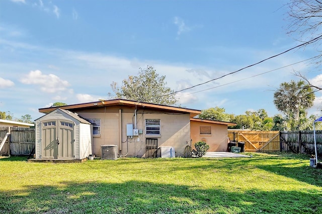 back of property featuring a lawn, central AC, and a shed