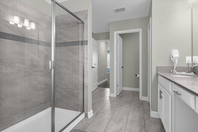 bathroom featuring tile patterned flooring, vanity, a textured ceiling, and walk in shower