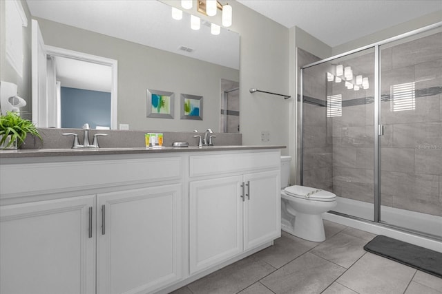 bathroom with tile patterned flooring, vanity, a shower with shower door, and toilet