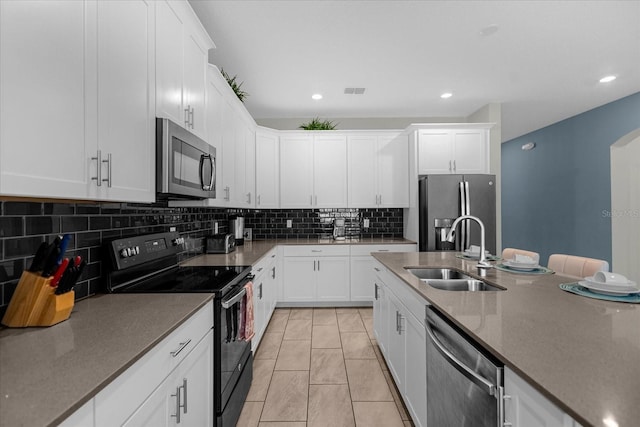 kitchen featuring backsplash, white cabinets, sink, light tile patterned floors, and appliances with stainless steel finishes