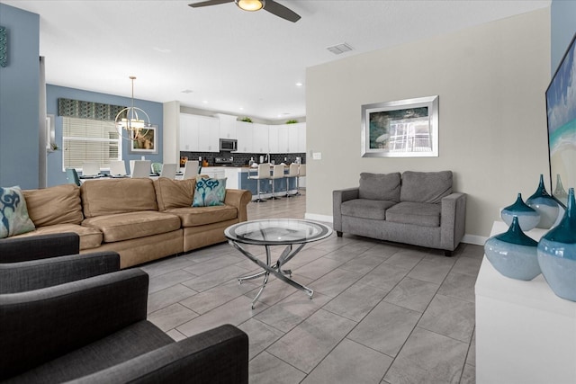 living room with ceiling fan with notable chandelier and light tile patterned floors