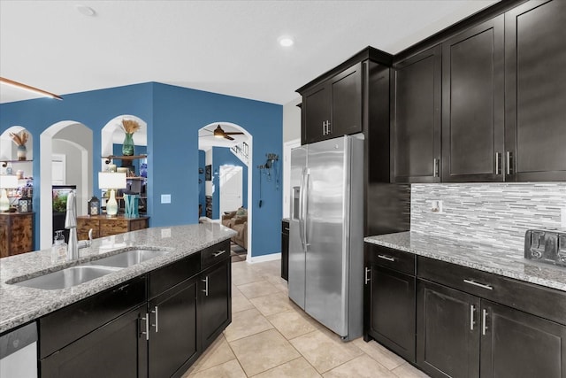 kitchen featuring ceiling fan, sink, stainless steel appliances, light stone counters, and decorative backsplash