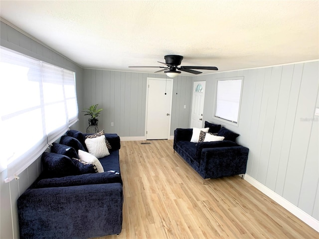 living room featuring ceiling fan, light hardwood / wood-style flooring, and wooden walls