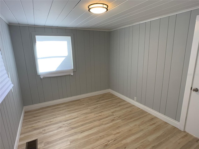 spare room featuring wood walls and light hardwood / wood-style floors