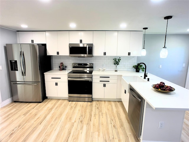 kitchen with sink, hanging light fixtures, decorative backsplash, white cabinetry, and stainless steel appliances