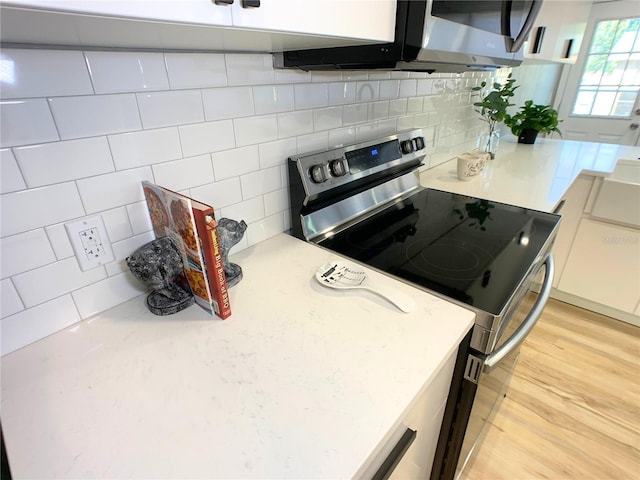 kitchen featuring range with electric stovetop, backsplash, white cabinets, and light wood-type flooring