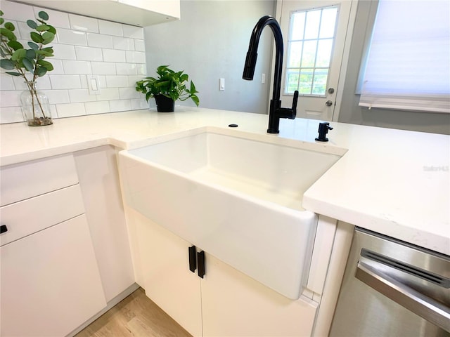 interior details featuring white cabinets, dishwasher, sink, and backsplash