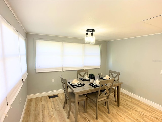 dining space featuring crown molding and light hardwood / wood-style flooring