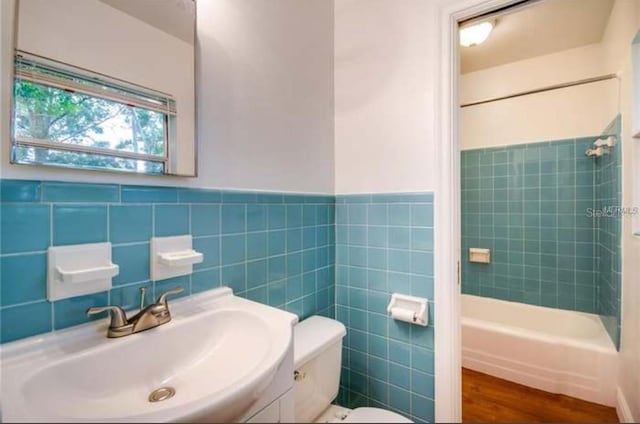 full bathroom featuring vanity, tiled shower / bath combo, tile walls, and toilet