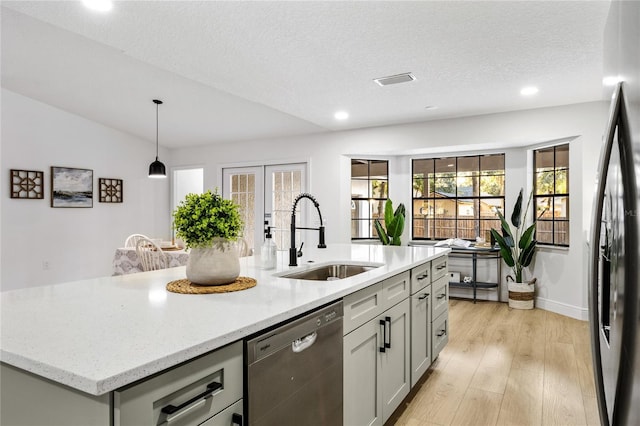 kitchen featuring an island with sink, light stone countertops, sink, black refrigerator with ice dispenser, and stainless steel dishwasher