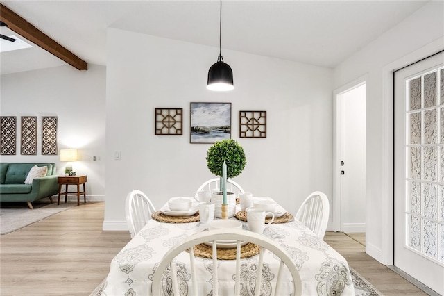 dining area featuring light hardwood / wood-style flooring and lofted ceiling with beams