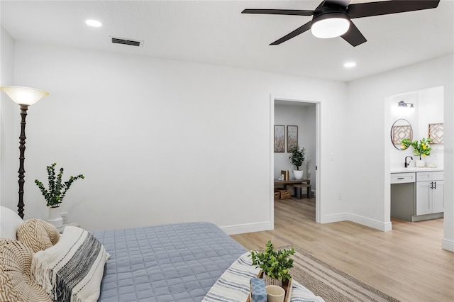 bedroom featuring ensuite bath, ceiling fan, light hardwood / wood-style flooring, and sink