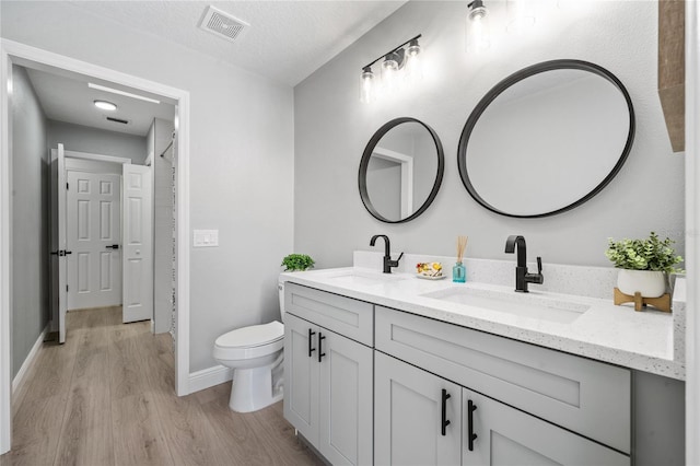 bathroom featuring a textured ceiling, toilet, vanity, and wood-type flooring