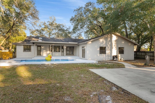 back of property with a fenced in pool and a patio