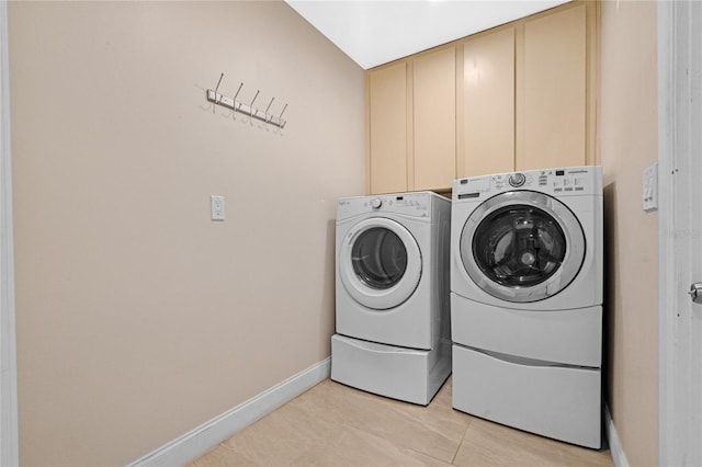 laundry room featuring cabinets, light tile patterned floors, and separate washer and dryer