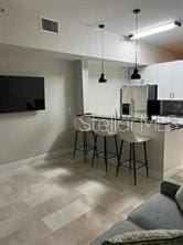 bar featuring stainless steel fridge, pendant lighting, decorative backsplash, and white cabinetry