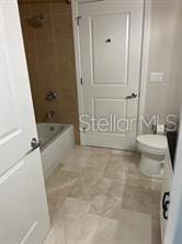 bathroom with toilet and tiled shower / bath