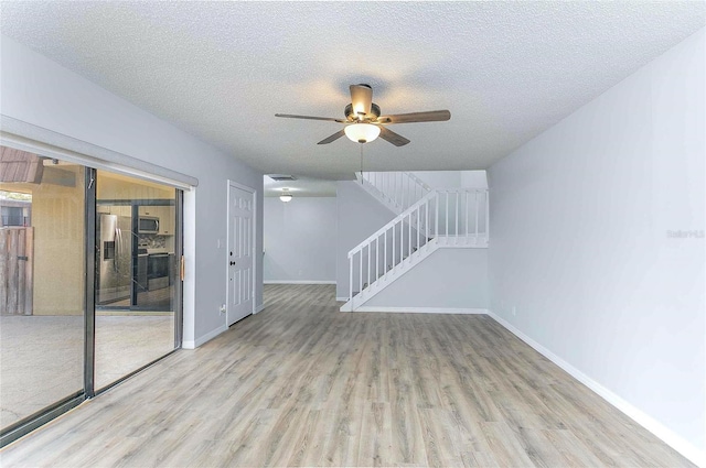 unfurnished living room featuring ceiling fan, a textured ceiling, and light wood-type flooring