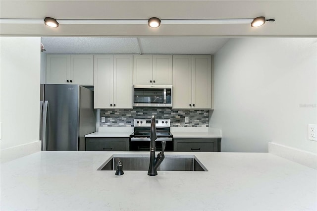 kitchen featuring appliances with stainless steel finishes, tasteful backsplash, gray cabinetry, and sink