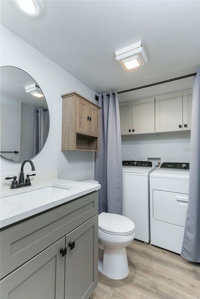 bathroom with hardwood / wood-style floors, vanity, toilet, and separate washer and dryer