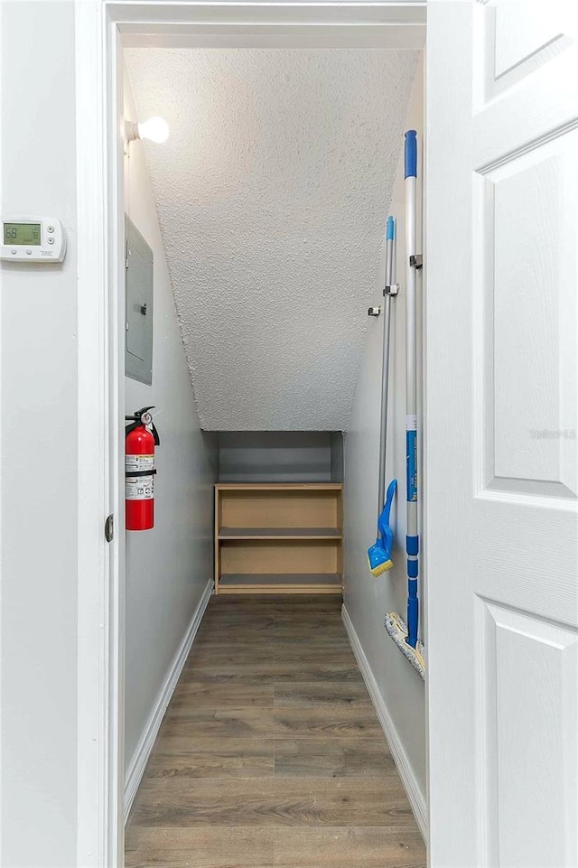 interior space with electric panel, hardwood / wood-style floors, and lofted ceiling