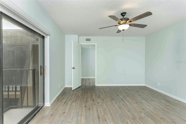 empty room with ceiling fan, light hardwood / wood-style flooring, and a textured ceiling