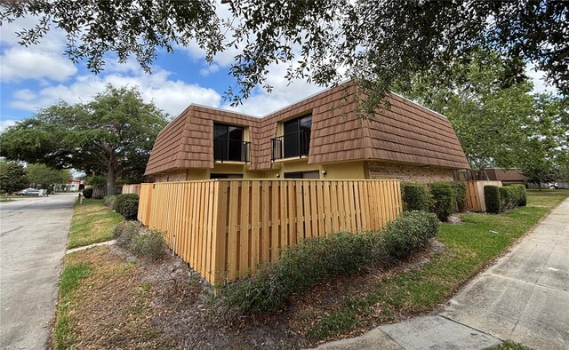 5341 Bamboo Ct Unit 418, Orlando, FL 32811 - view of property exterior with brick siding, a balcony, fence, and mansard roof