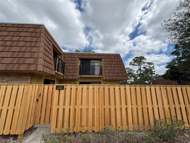 5341 Bamboo Ct Unit 418, Orlando, FL 32811 - view of side of home featuring brick siding, a fenced front yard, a balcony, and mansard roof