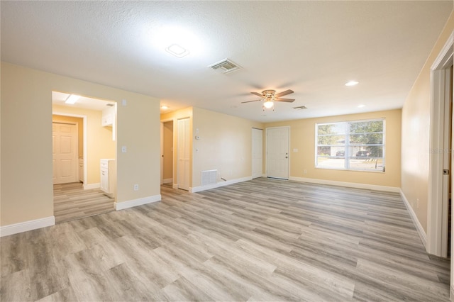 empty room featuring light hardwood / wood-style floors, ceiling fan, and a textured ceiling