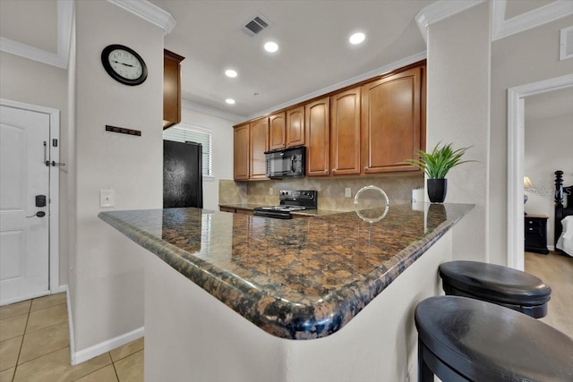 kitchen with black appliances, dark stone countertops, kitchen peninsula, and light tile patterned floors