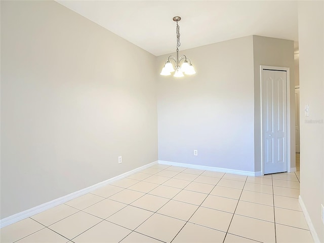 empty room with a notable chandelier and light tile patterned flooring