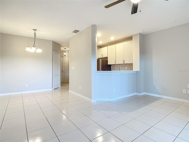 empty room with ceiling fan with notable chandelier, light tile patterned floors, and sink