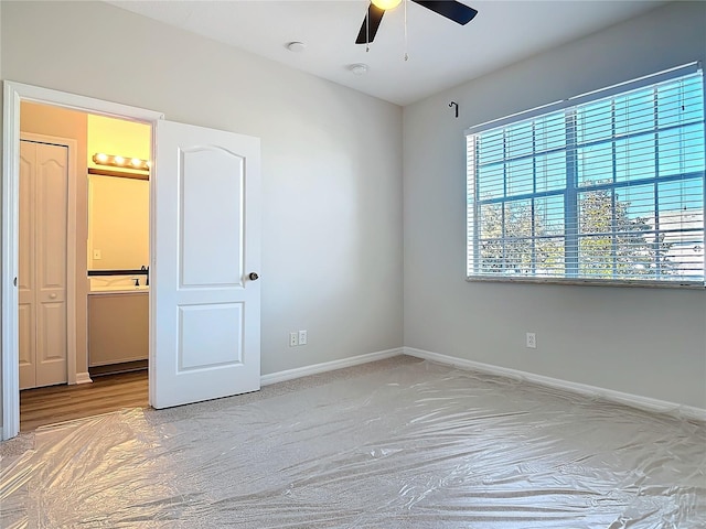 unfurnished bedroom with ceiling fan and connected bathroom