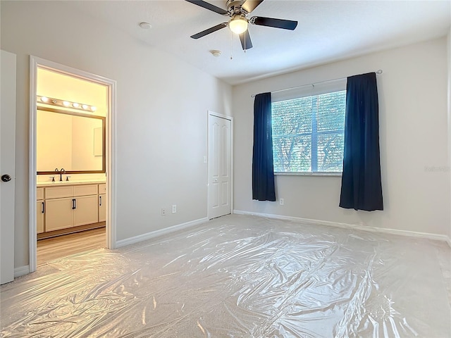 bedroom with a closet, ensuite bathroom, sink, and ceiling fan