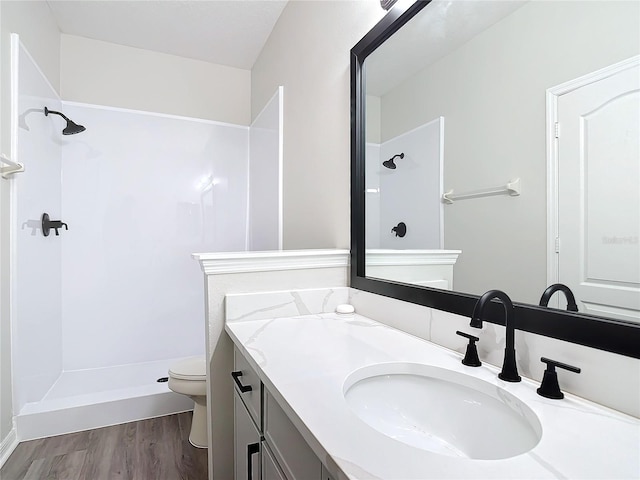 bathroom with hardwood / wood-style flooring, vanity, toilet, and walk in shower