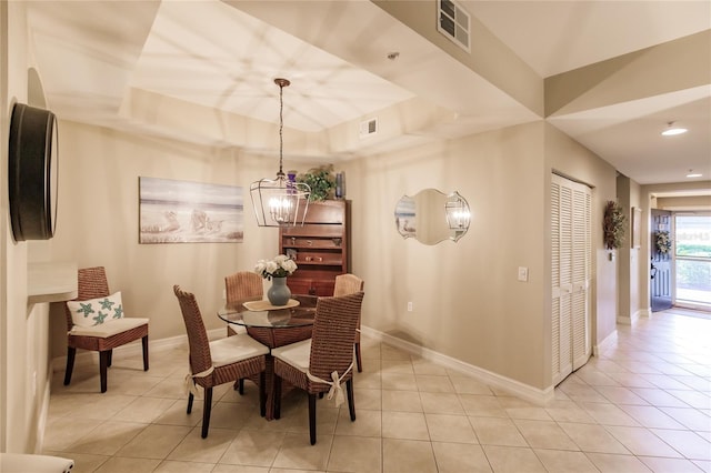 dining area featuring a notable chandelier, a tray ceiling, and light tile patterned floors