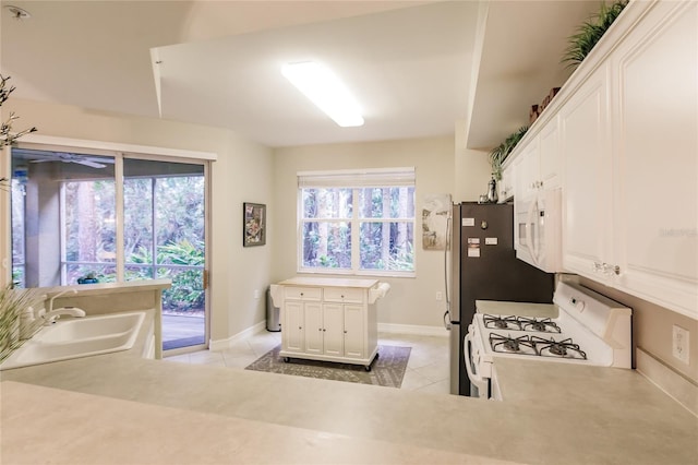 kitchen featuring light tile patterned flooring, sink, kitchen peninsula, white appliances, and white cabinets