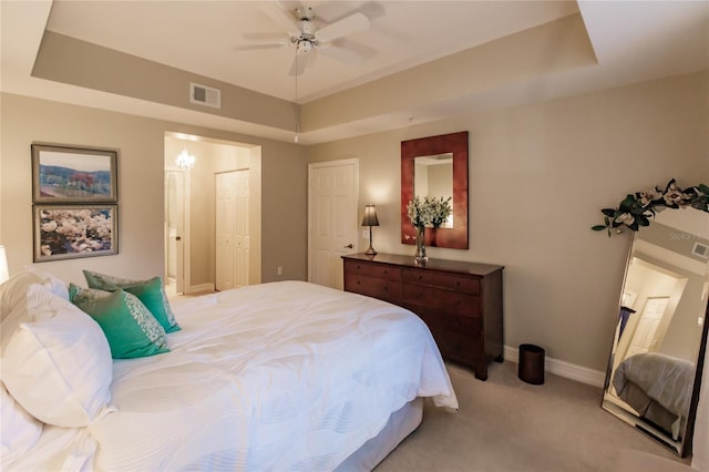 carpeted bedroom with a raised ceiling and ensuite bathroom