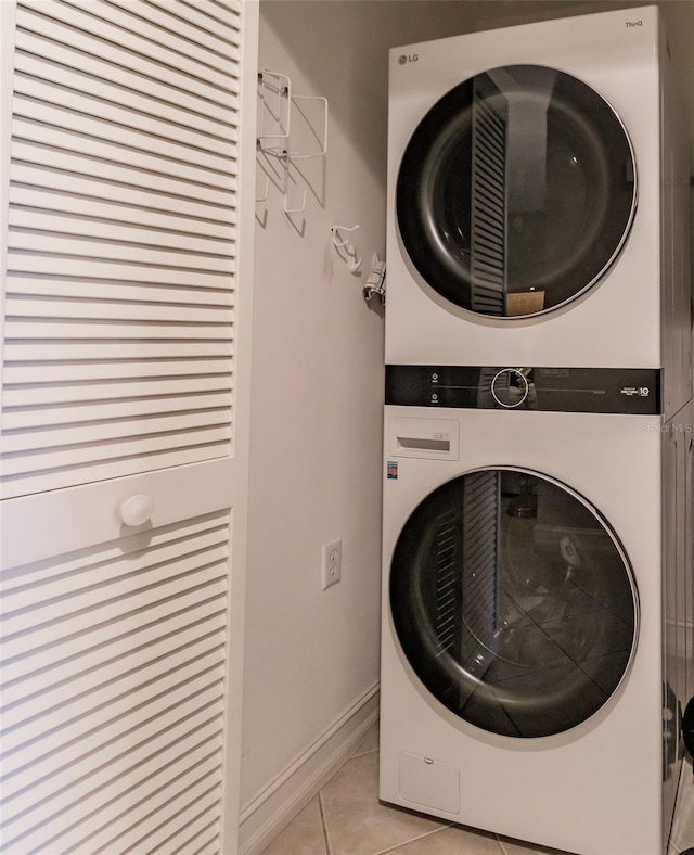 clothes washing area with stacked washer and clothes dryer and light tile patterned floors