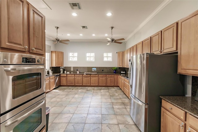 kitchen with crown molding, dark stone counters, ceiling fan, and appliances with stainless steel finishes